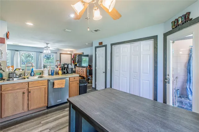 a kitchen with stainless steel appliances granite countertop a refrigerator a sink dishwasher a stove and white cabinets with wooden floor