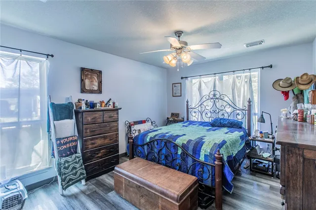 a bedroom with a bed a dresser and wooden floor