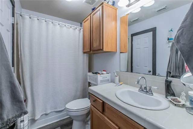 a bathroom with a granite countertop sink toilet and a mirror