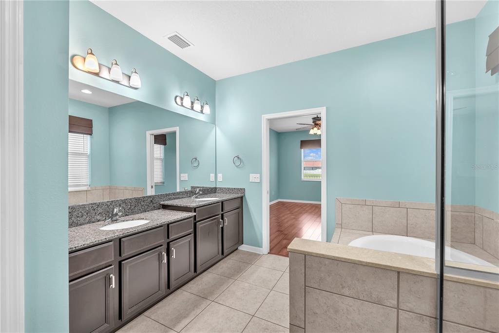 11236 77th Street East Parrish, FL 34219 - Photo 18 of 53 a spacious bathroom with a granite countertop sink a mirror and a