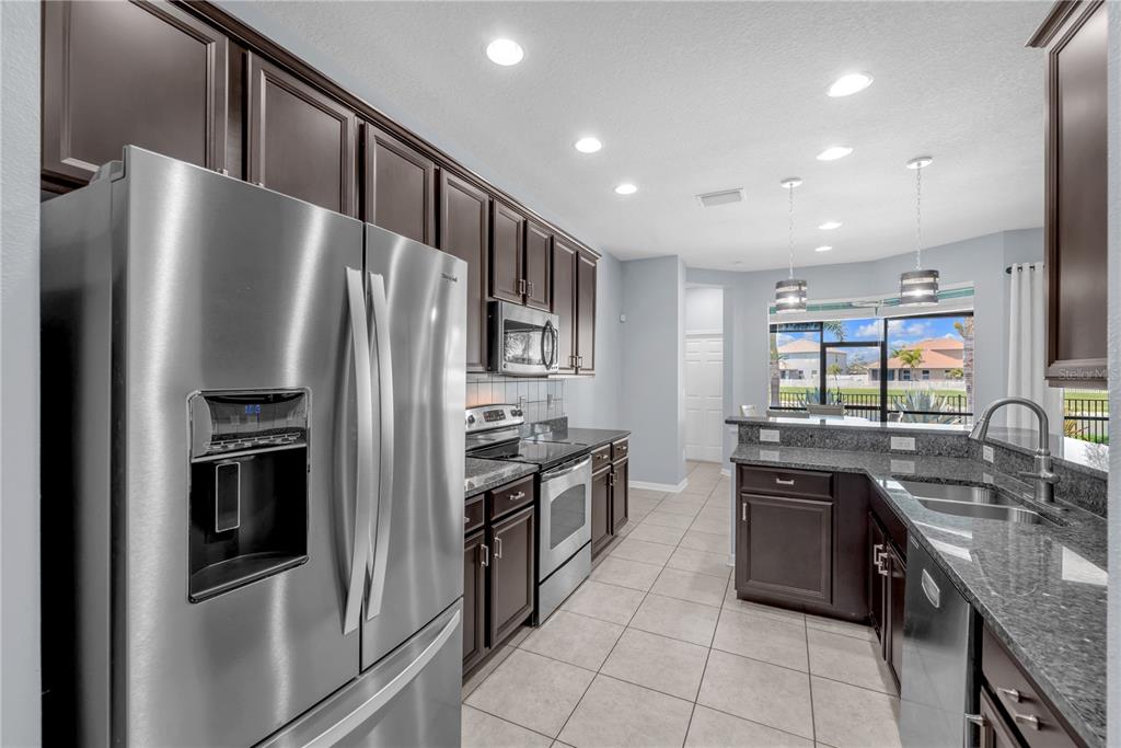 11236 77th Street East Parrish, FL 34219 - Photo 5 of 53 a kitchen with stainless steel appliances granite countertop a refrigerator a sink a stove and a microwave