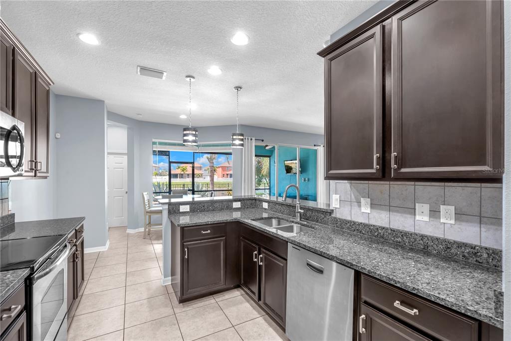 11236 77th Street East Parrish, FL 34219 - Photo 6 of 53 a kitchen with stainless steel appliances granite countertop a sink and stove