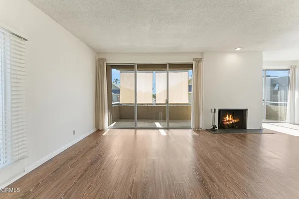 an empty room with wooden floor fireplace and windows