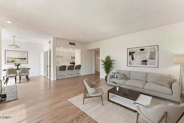 a living room with furniture and a dining table with wooden floor
