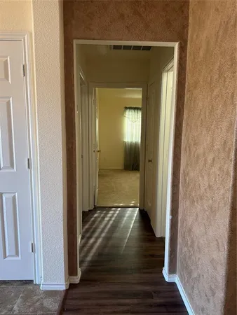 a view of a hallway with wooden floor and a room