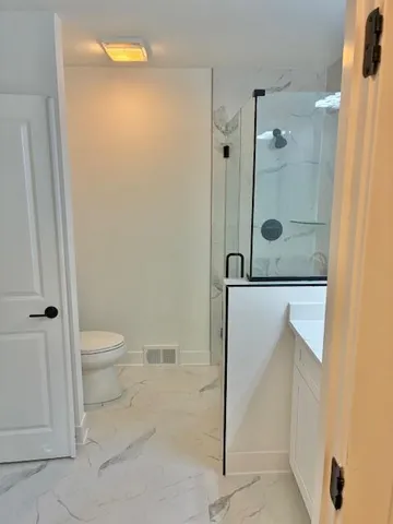 a bathroom with a granite countertop sink a toilet and shower