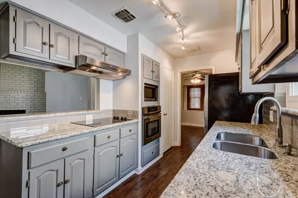a kitchen with stainless steel appliances granite countertop a sink refrigerator and cabinets