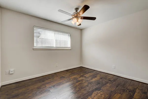an empty room with wooden floor and ceiling fan