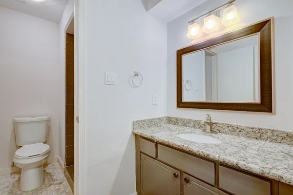 a bathroom with a granite countertop toilet sink and mirror
