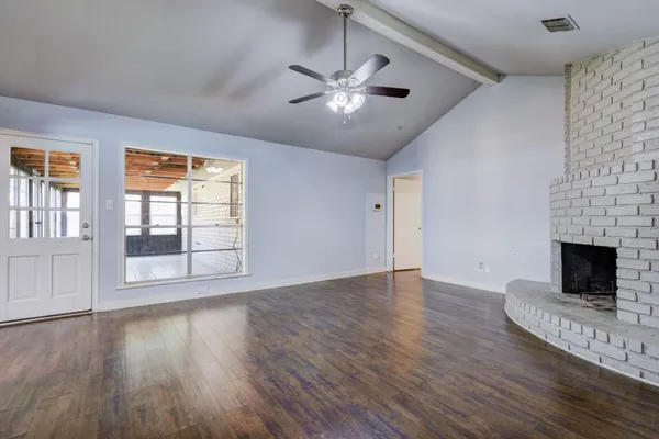 a view of an empty room with wooden floor and a fireplace