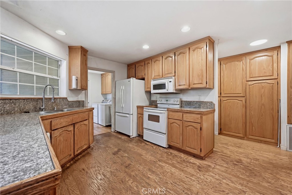 16965 Spruce Grove Road Hidden Valley Lake, CA 95467 - Photo 10 of 34 a kitchen with granite countertop a refrigerator oven a sink dishwasher and white cabinets with wooden floor
