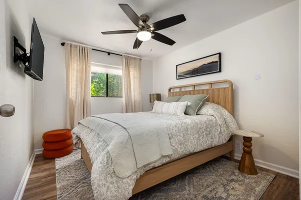 a bedroom with a bed a flat screen tv and a ceiling fan