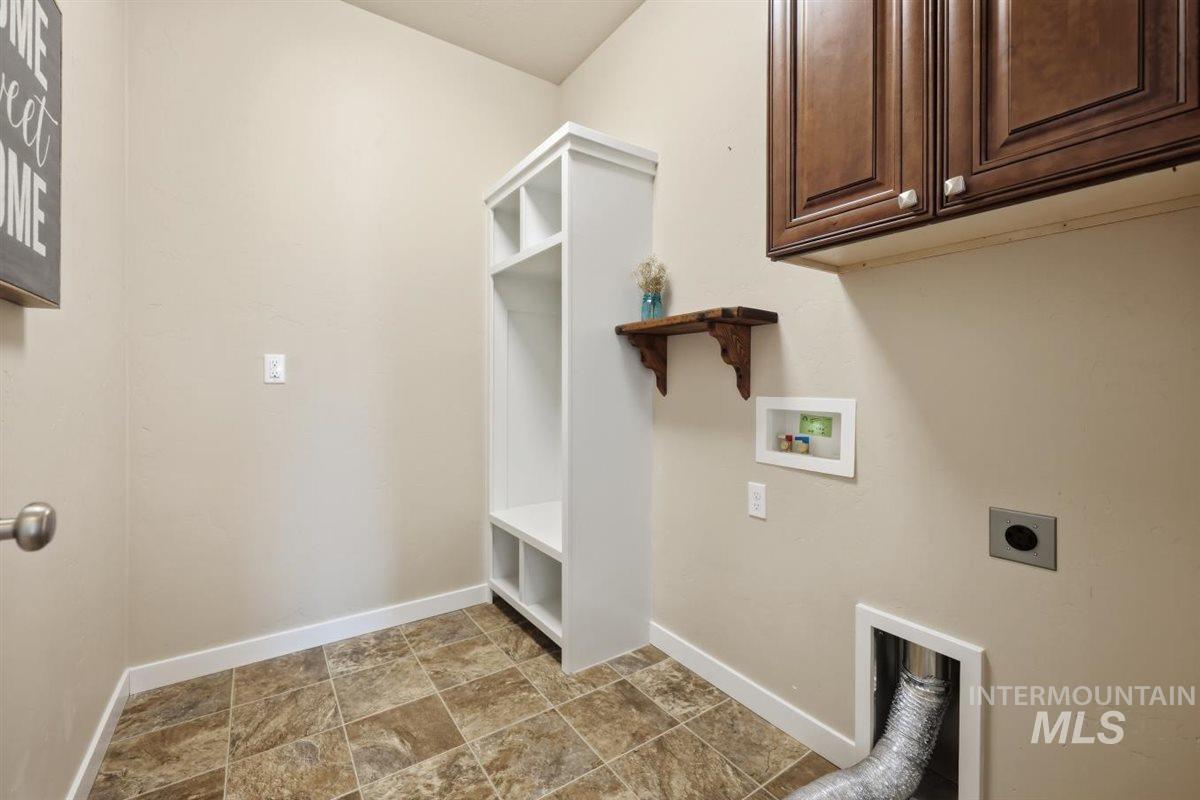13496 Hockberger Ranch Road Caldwell, ID 83607 - Photo 21 of 40 Laundry area featuring built-in cabinetry, an integrated white storage bench with shelving, rich wood-finish upper cabinets, and durable tile-look flooring