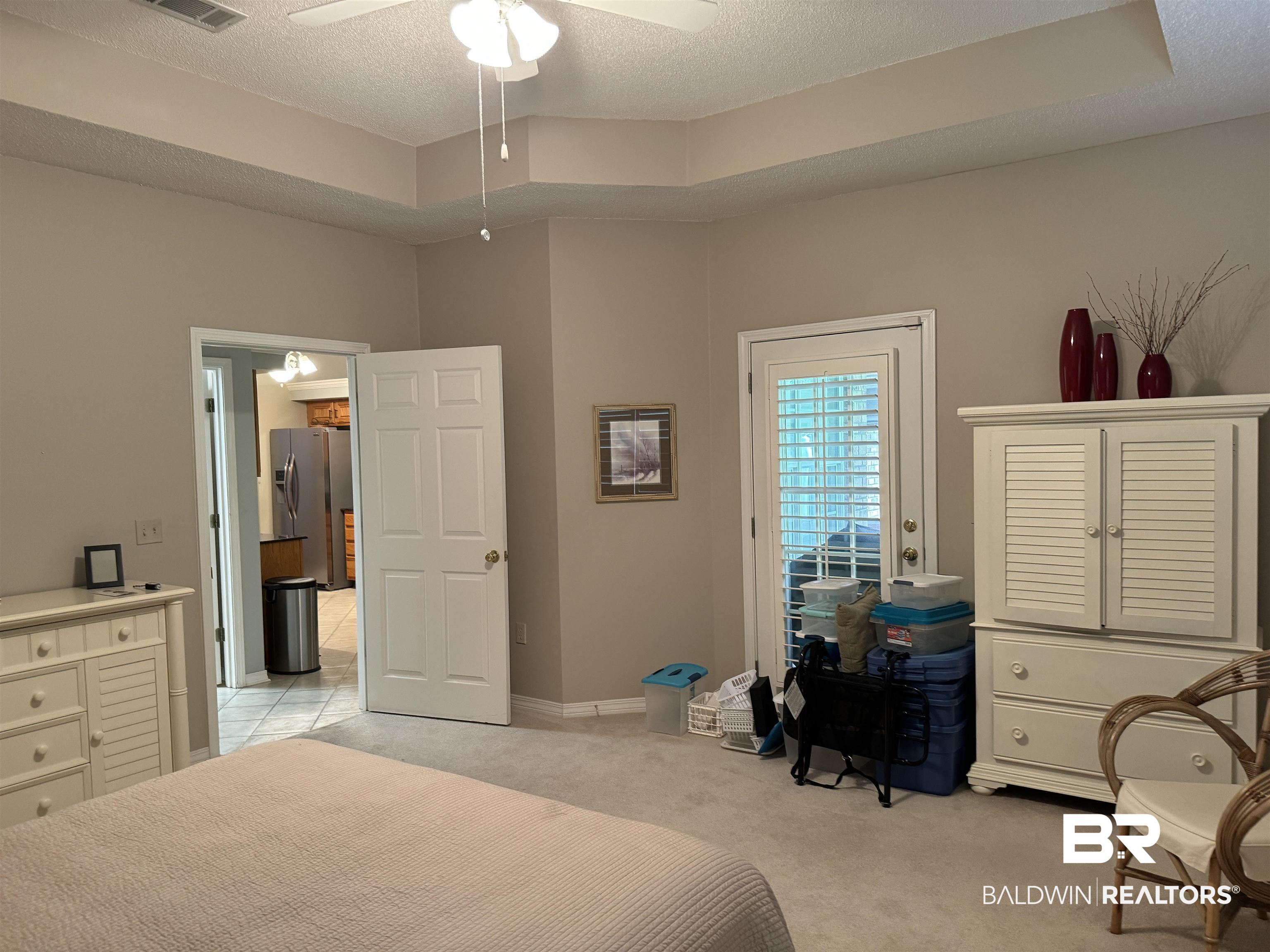 9139 Clubhouse Drive Foley, AL 36535 - Photo 21 of 30 Bedroom with a textured ceiling, light carpet, a tray ceiling, ceiling fan, and stainless steel fridge