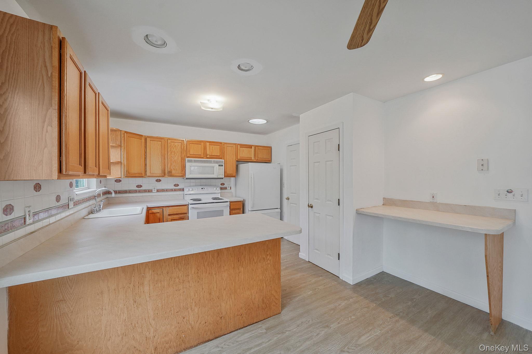 22 Wright Road Manorville, NY 11949 - Photo 12 of 47 a large kitchen with stainless steel appliances a large counter top a stove and a refrigerator