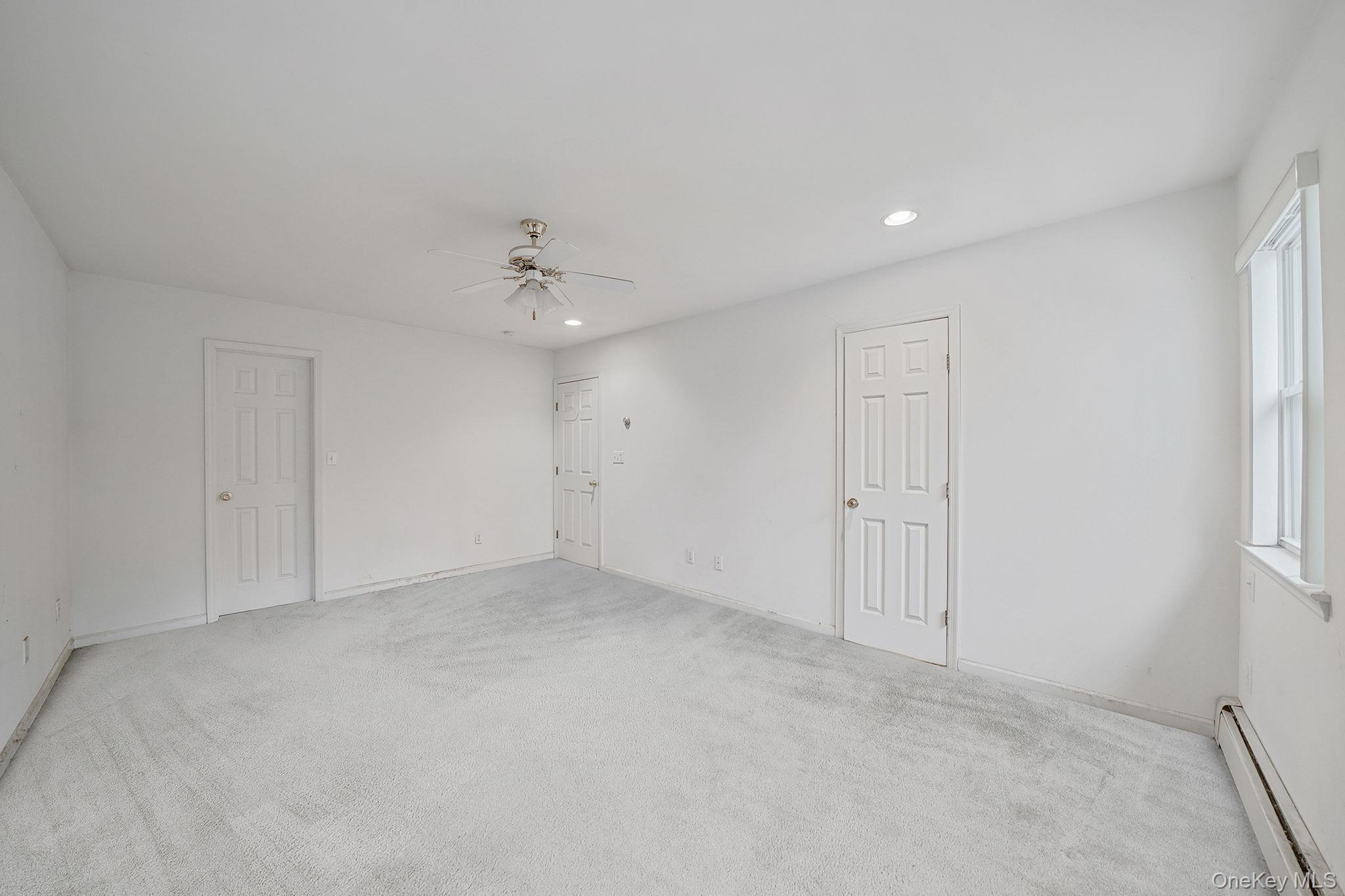 22 Wright Road Manorville, NY 11949 - Photo 27 of 47 an empty room with a ceiling fan and a window
