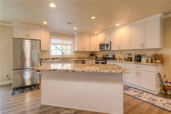 a kitchen with stainless steel appliances granite countertop a refrigerator a stove a sink and white cabinets