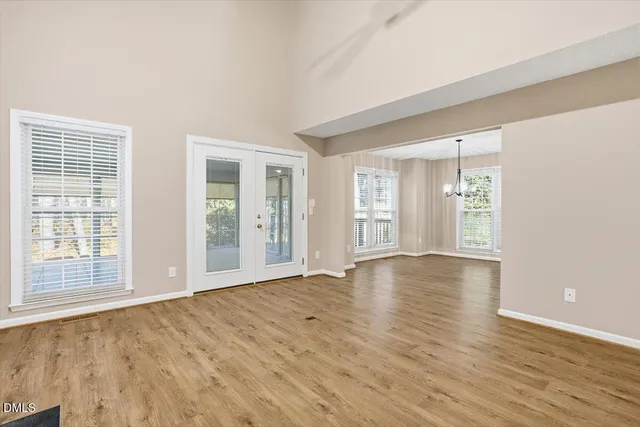 an empty room with wooden floor fireplace and windows