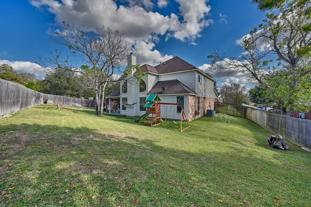 a view of house with backyard and a slide