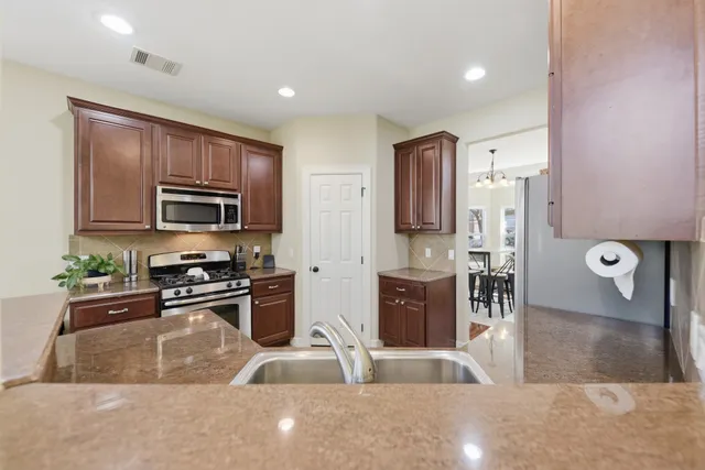 a kitchen with stainless steel appliances granite countertop a refrigerator a stove top oven a sink and dishwasher