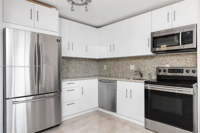 a kitchen with stainless steel appliances white cabinets white stove a microwave and a refrigerator