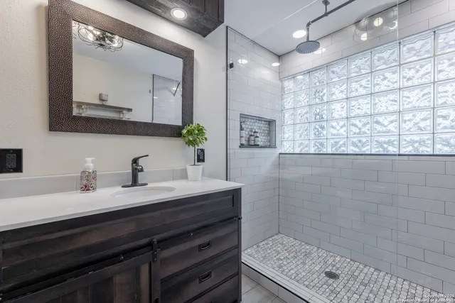 a bathroom with a granite countertop sink a mirror and shower