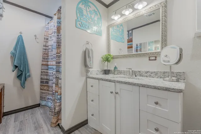 a bathroom with a granite countertop sink a mirror and shower