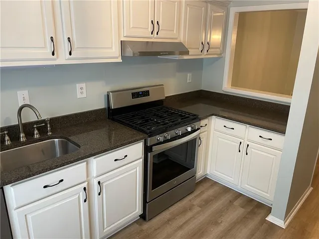 a kitchen with granite countertop white cabinets and appliances