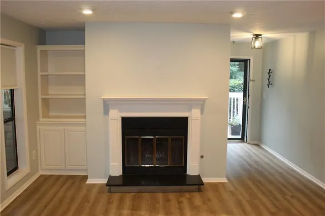 a view of an empty room with wooden floor and a fireplace