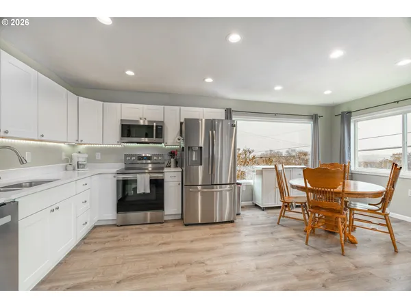 a kitchen with stainless steel appliances granite countertop a stove a sink a refrigerator with a dining table and chairs