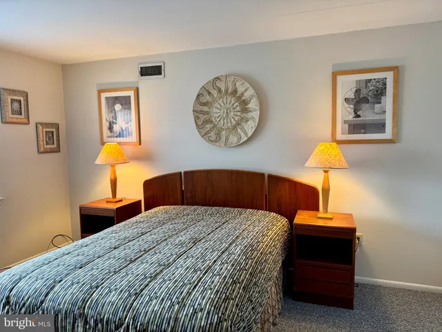 a bedroom with a bed and a lamp on dresser