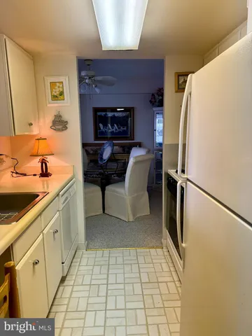 a hallway with cabinets a refrigerator and a sink