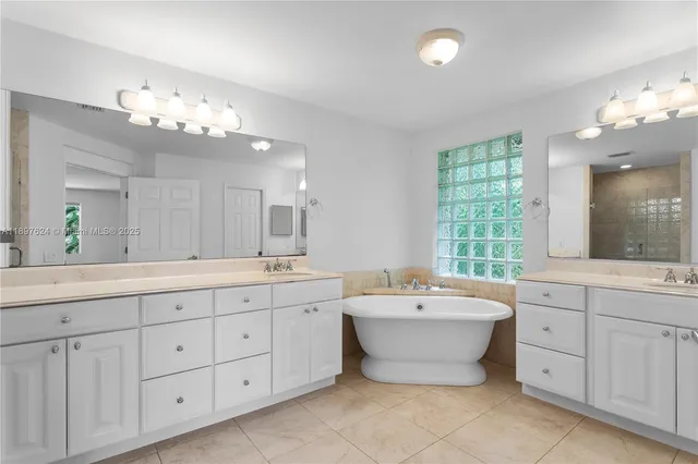 a spacious bathroom with a double vanity sink mirror and bathtub