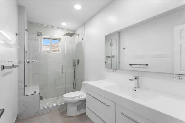 a bathroom with a shower sink vanity mirror and toilet