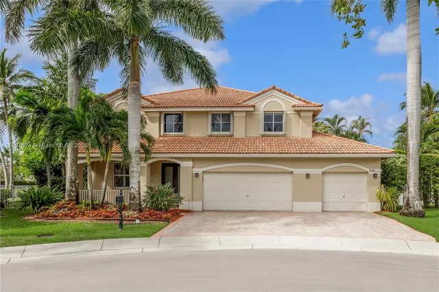 a front view of a house with a garden and palm trees