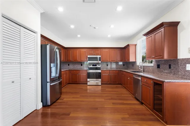 a large kitchen with stainless steel appliances granite countertop a refrigerator and a stove top oven