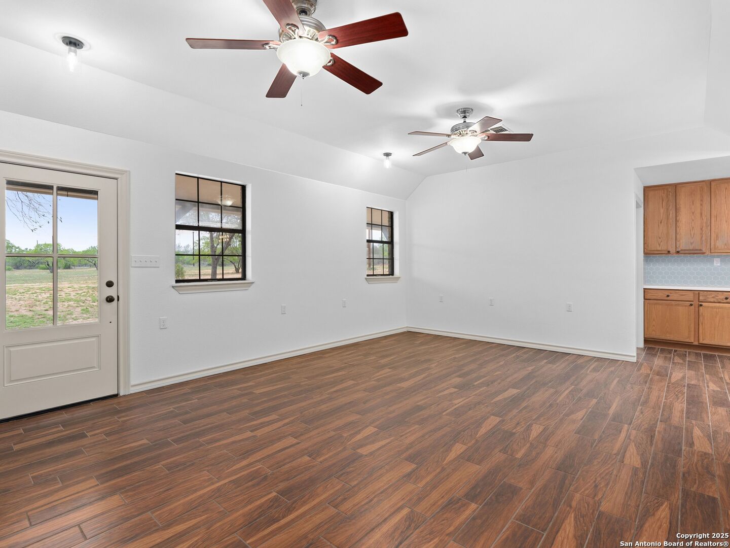 601 Wild Flower Drive Lytle, TX 78052 - Photo 13 of 50 an empty room with wooden floor chandelier fan and windows