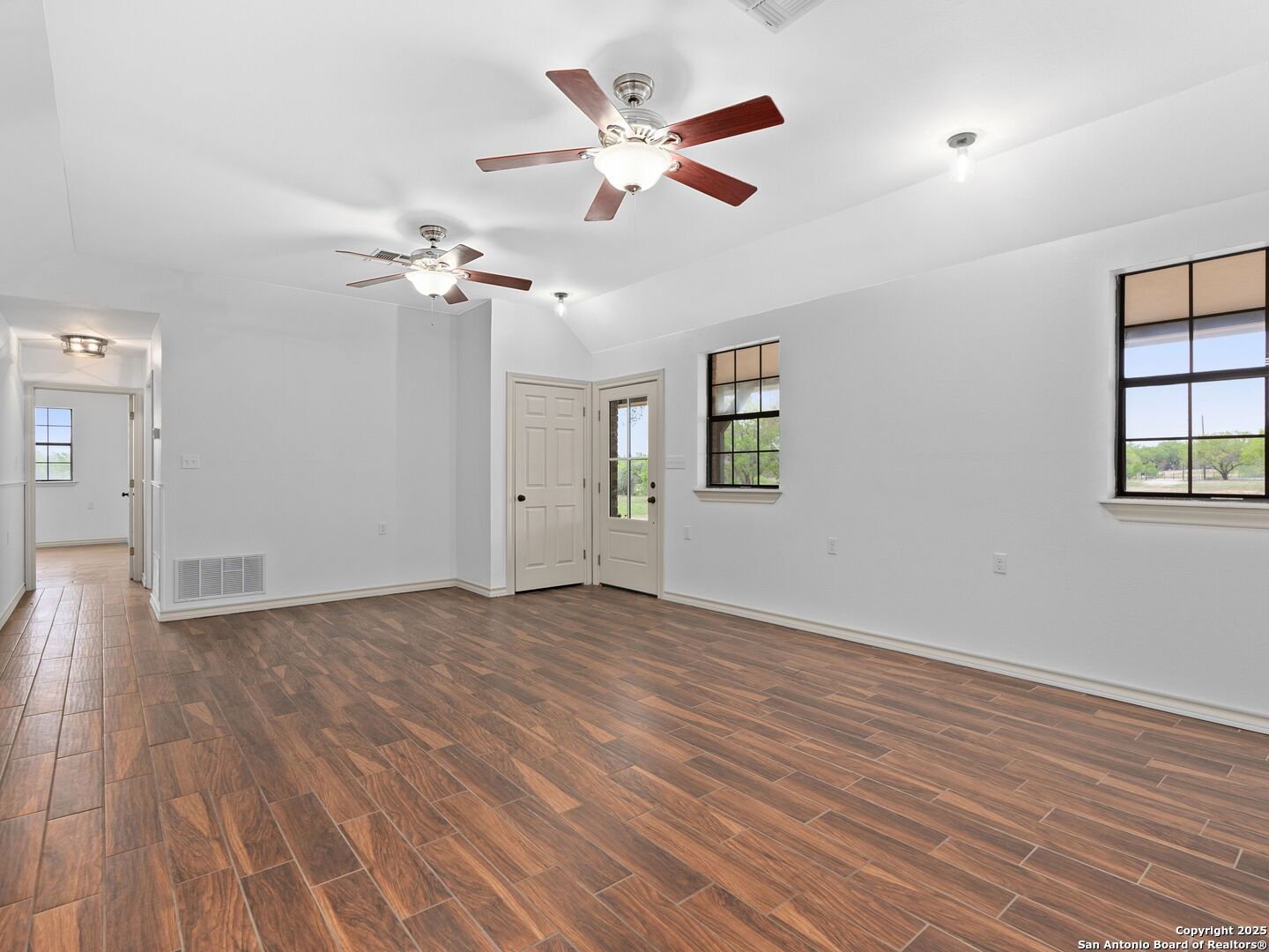 601 Wild Flower Drive Lytle, TX 78052 - Photo 16 of 50 an empty room with wooden floor chandelier fan and windows