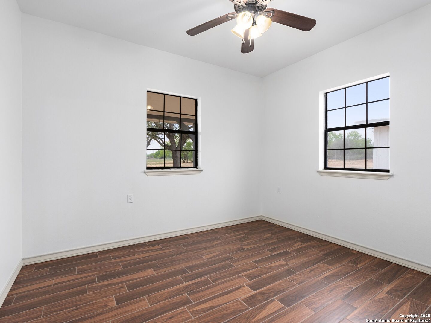 601 Wild Flower Drive Lytle, TX 78052 - Photo 22 of 50 an empty room with wooden floor chandelier fan and windows