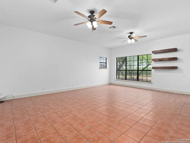 an empty room with windows and ceiling fan