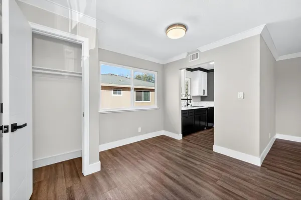 a view of an empty room with wooden floor and a window
