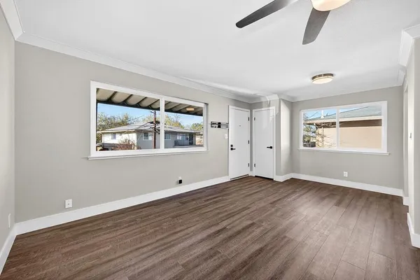 an empty room with wooden floor and ceiling fan