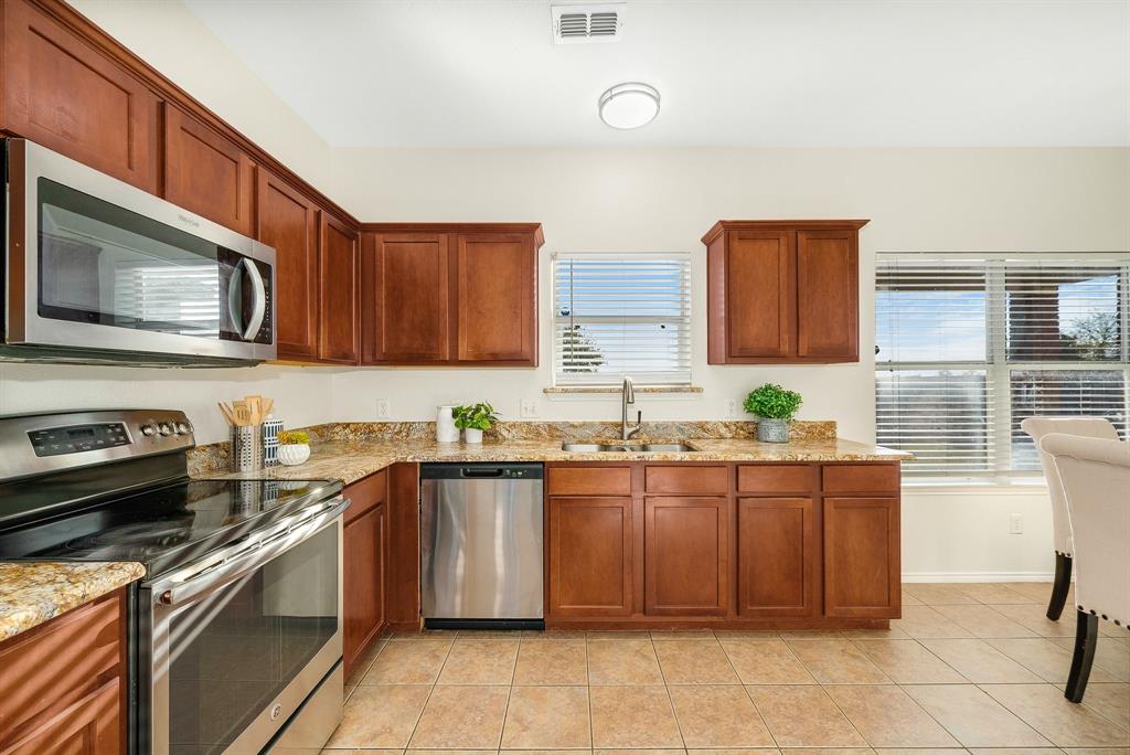 2400 Rushing Springs Drive Fort Worth, TX 76118 - Photo 15 of 40 a kitchen with stainless steel appliances granite countertop a sink and stove top oven