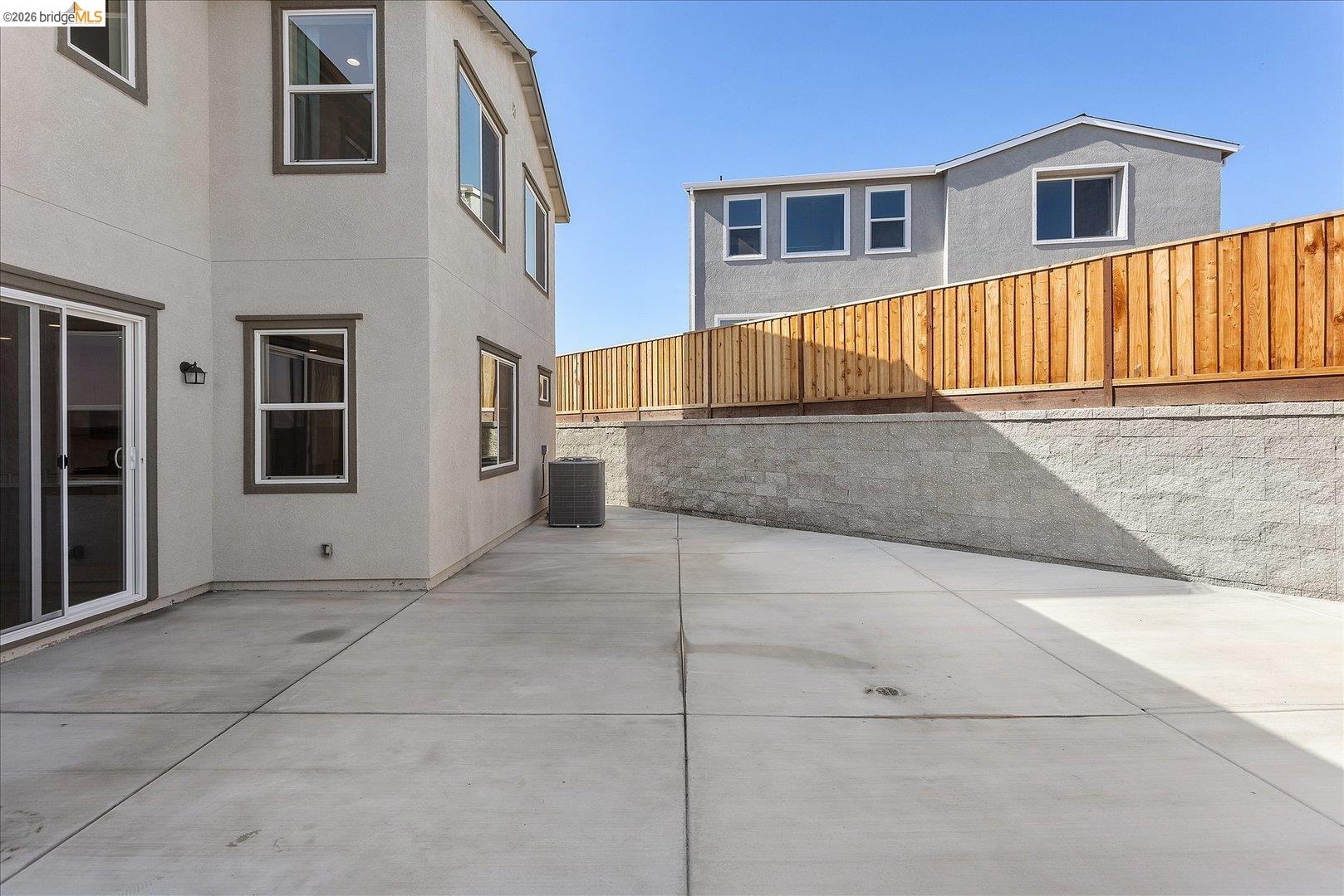 5601 Ridgepoint Way Antioch, CA 94531 - Photo 43 of 59 Expansive concrete patio with sliding glass doors, contemporary exterior lighting, and a retaining wall featuring a new privacy fence