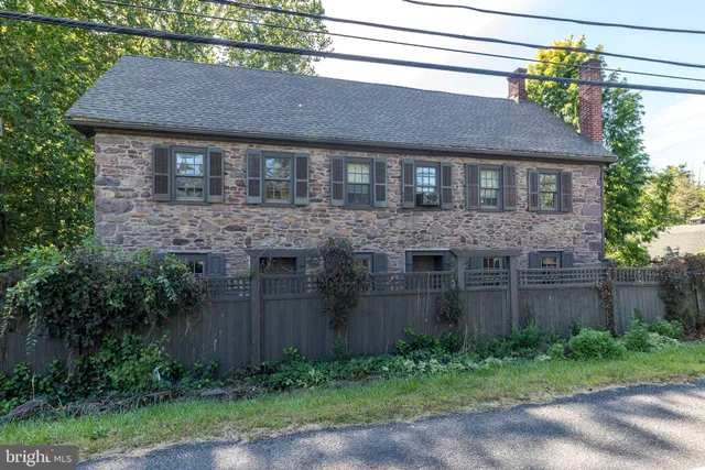 a brick house with a yard plants and large tree