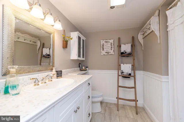 a bathroom with a granite countertop sink mirror vanity and toilet