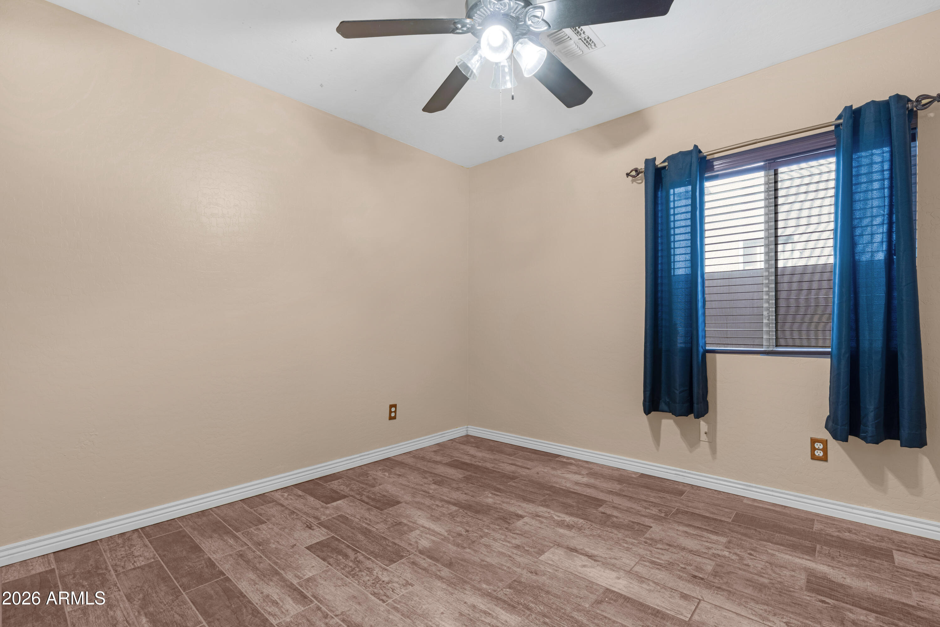 12018 West Almeria Road Avondale, AZ 85392 - Photo 22 of 39 a view of an empty room with wooden floor and fan