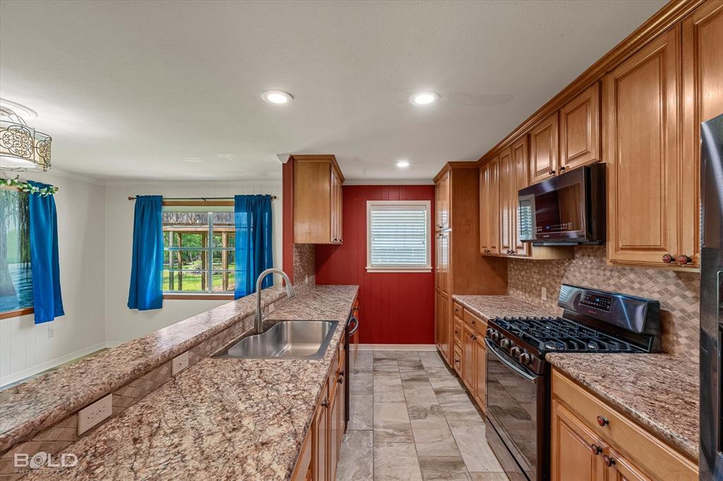 225 Marie Road Ringgold, LA 71068 - Photo 27 of 40 Kitchen featuring wood cabinetry, stainless steel appliances, granite-style countertops, and a tile backsplash