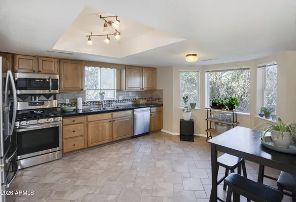 a kitchen with granite countertop a stove a sink a refrigerator a dining table and chairs