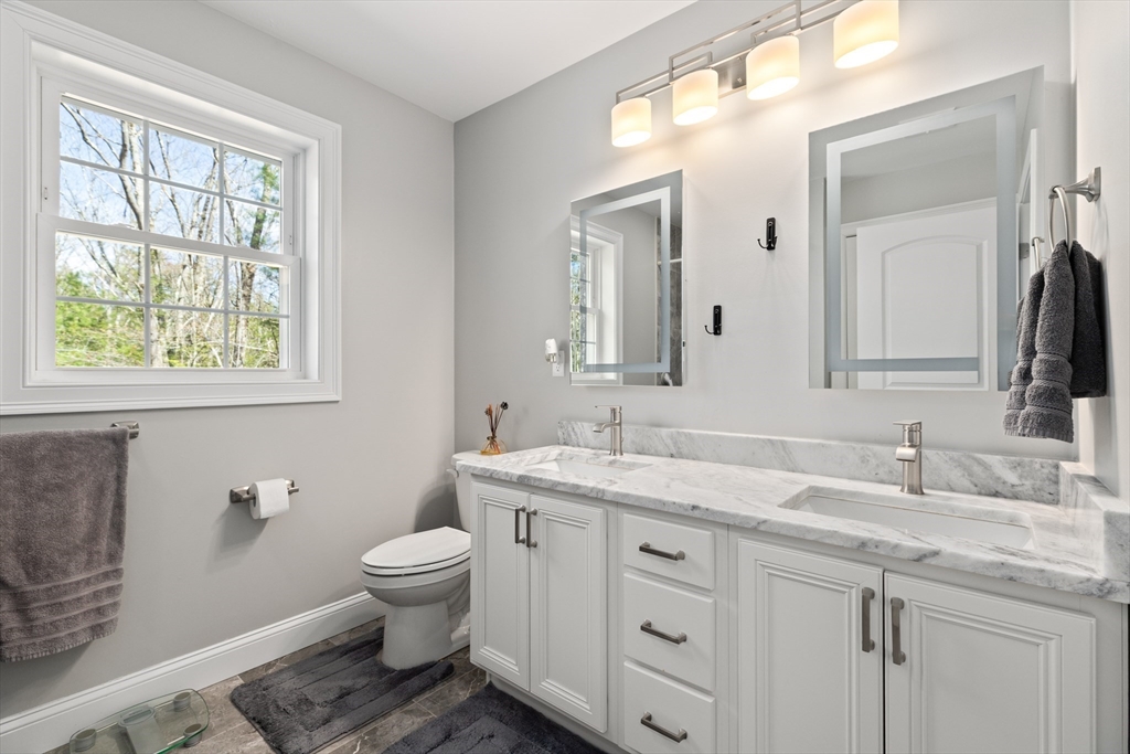 526 Hubbardston Road Templeton, MA 01468 - Photo 18 of 32 a bathroom with a granite countertop toilet a sink a large mirror and a window
